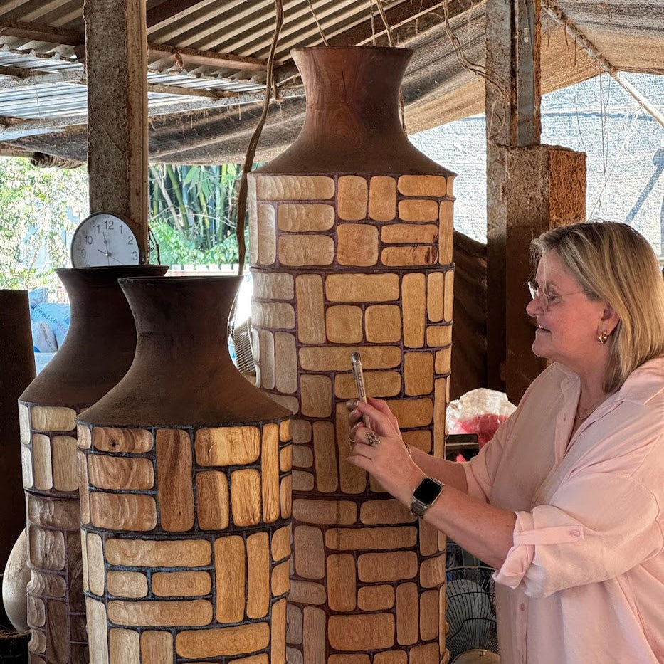 Eline selecteert handgemaakte houten vazen bij een lokale maker in Thailand.